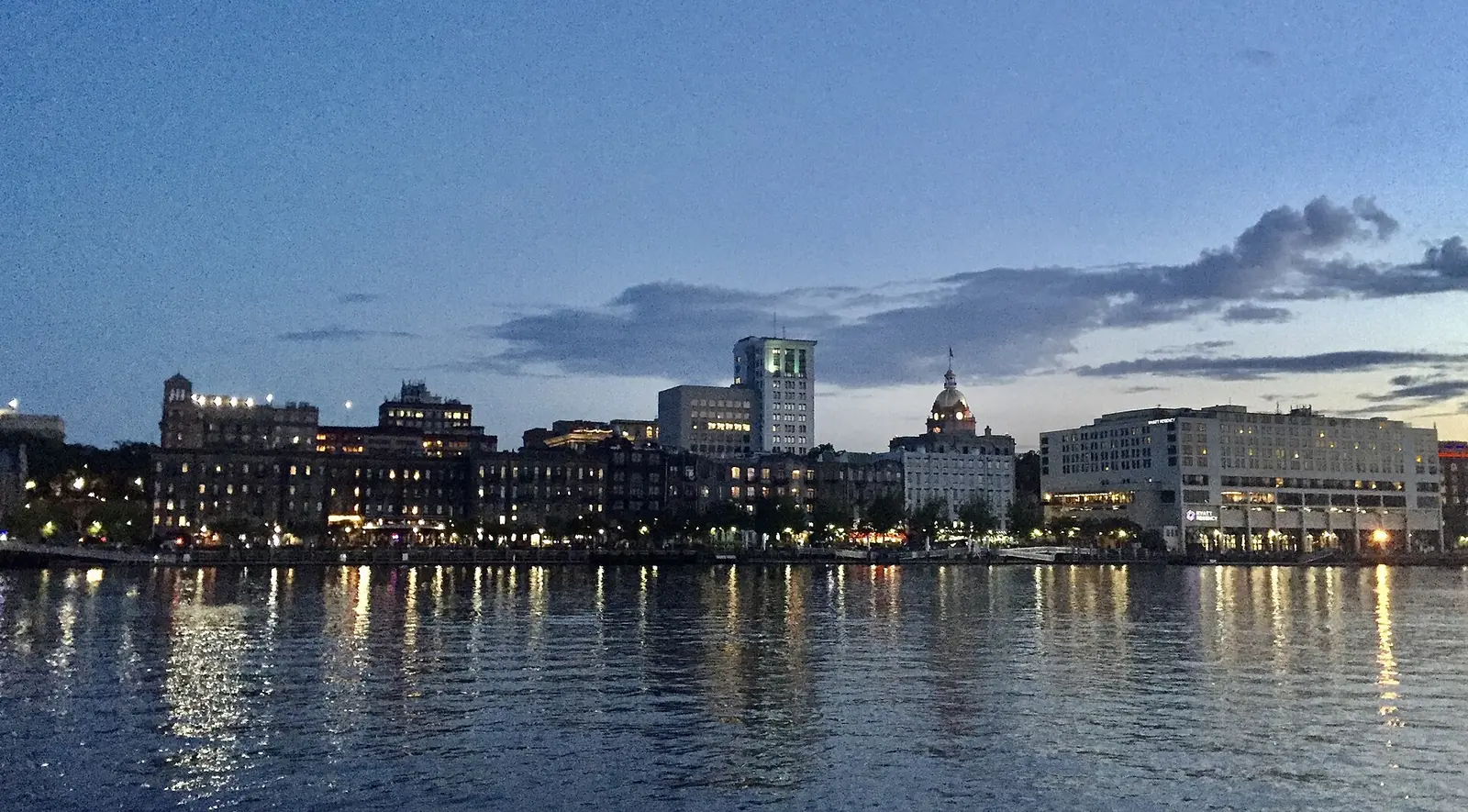 The Savannah waterfront and the gold dome of City Hall at dusk, seen across the Savannah River.